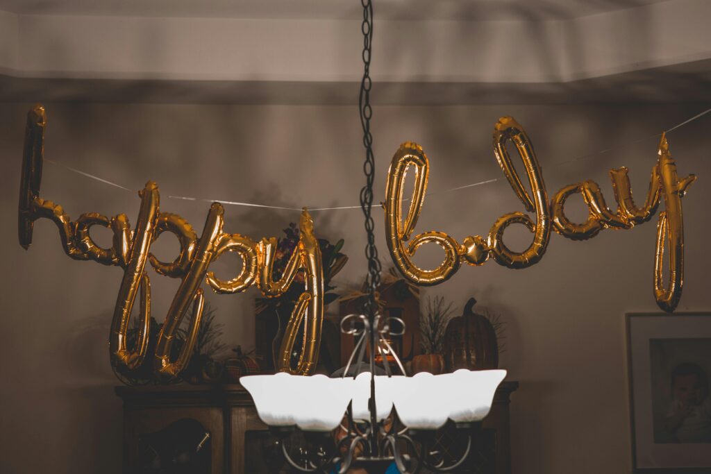 pexels photo 1543762 1543762 Festive gold balloons spelling 'happy bday' hang indoors, ideal for party themes.
